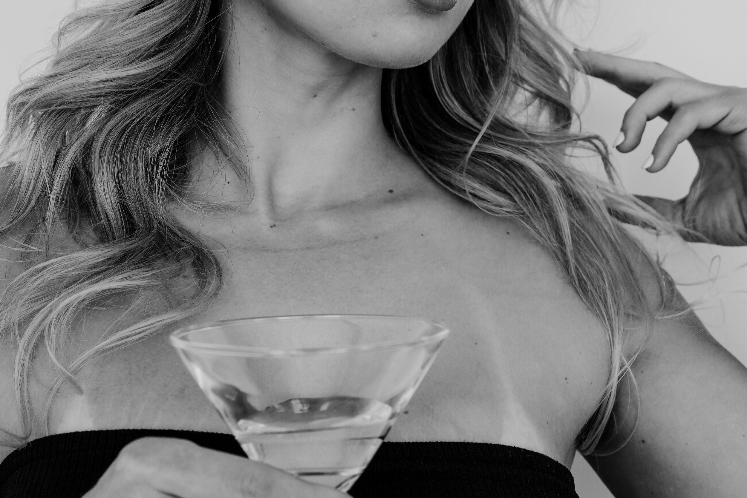 Woman holding a martini glass against a plain background