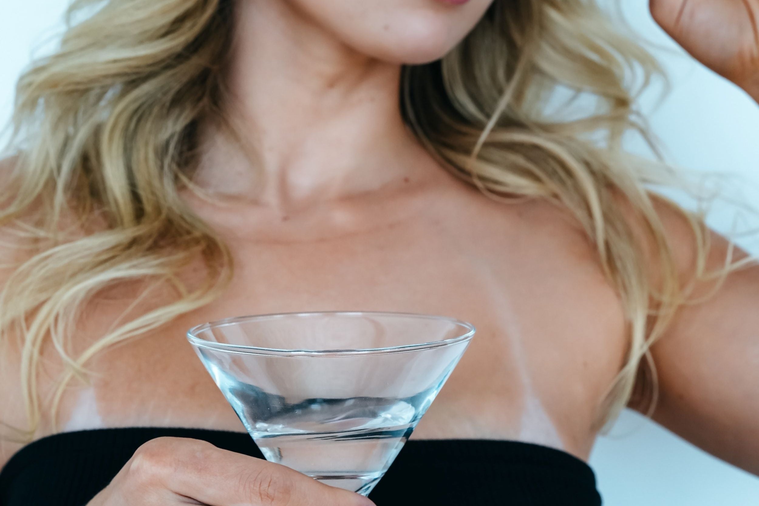Woman holding a martini glass against a light blue background